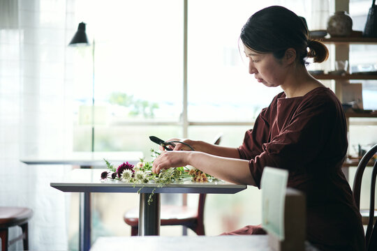 開店前のカフェで花をいける日本人女性