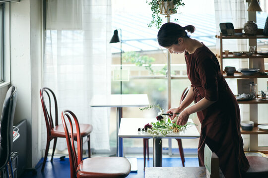 開店前のカフェで花をいける日本人女性