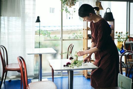 開店前のカフェで花をいける日本人女性