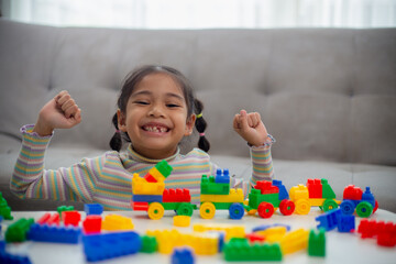 Adorable little girl playing toy blocks in a bright room.