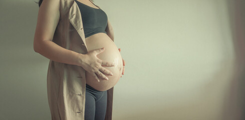 Pregnant woman's belly, holding her hands on pregnant belly. Young woman expecting a baby....