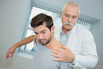 Fototapeta premium senior physiotherapist massaging the neck of young patient