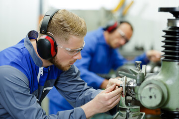 engineers working with factiry machinery wearing earmuffs