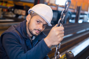 portrait of male factory worker holding chain