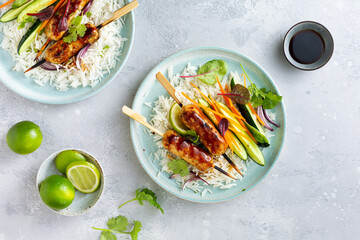 Asian-style kebabs with white rice and a side dish of vegetables