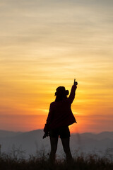 Fototapeta premium Silhouette of man hold up hands on the peak of mountain,success concept