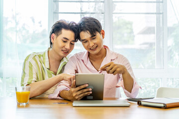 Attractive male lgbtq collegues working together with using digital tablet and paper showing graphic chart in living room, Lgbt love concept