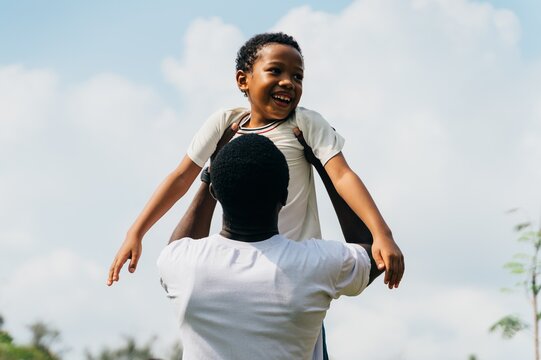 Father's Day Love: African American Dad Embracing Son in sunny day in the park