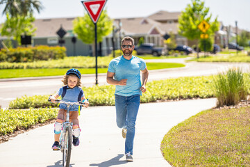 father and son on bicycle at fathers day. active father setting a example for fathers son. fathers parenting with son outdoor. childhood of son supported by fathers care. having fun