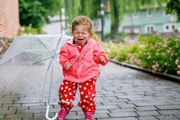 Cute adorable crying sad toddler girl on a walk. Little baby child going for walk with parents....