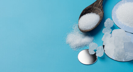 Heap of white Misri rock candy sweetener and granulated sugar on blue background