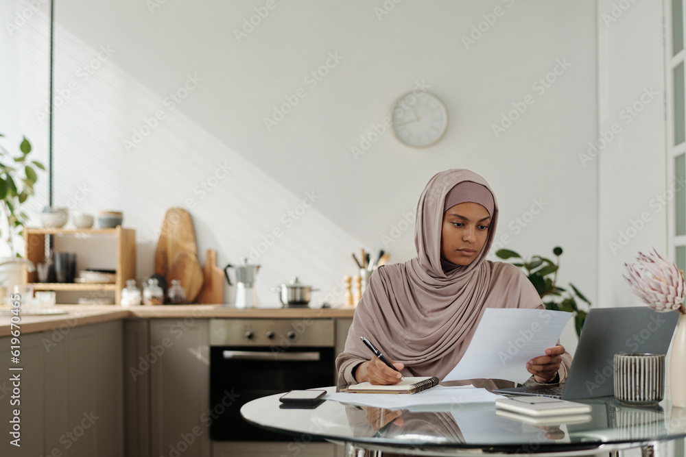 Poster serious female auditor with business document looking through its main points and making notes in co