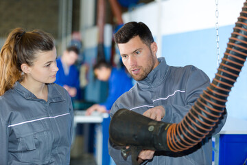 mechanic showing intern the extractor to remove fumes