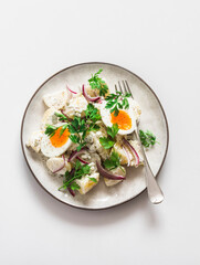 Classic potato  and boiled egg salad with red onion and cilantro on a light background, top view