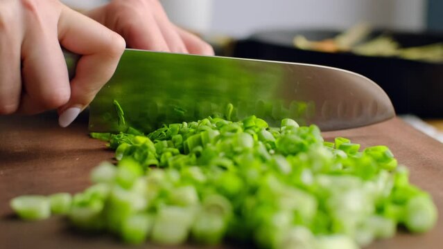 Chopping spring onion. Chef cutting raw green onion with knife, chopped organic vegetable ingredient for cooking, healthy salad spice flavoring