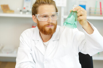 man looking at liquid in flask