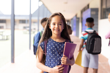 Portrait of smiling cacuasian schoolgirl in elementary school corridor, with copy space