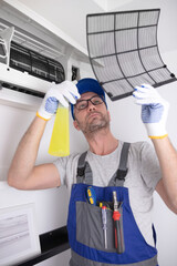 Service guy cleaning and maintaining air condition unit.