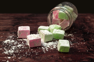 Colored portion scrubs in the form of sweets oriental sweets sprinkled with corn starch a wooden background