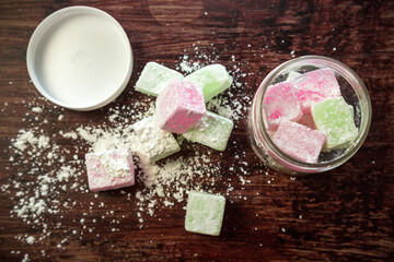 Colored portion scrubs in the form of sweets oriental sweets sprinkled with corn starch on a wooden background