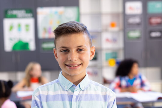 Portrait of happy, smiling caucasian schoolboy in classroom with copy space