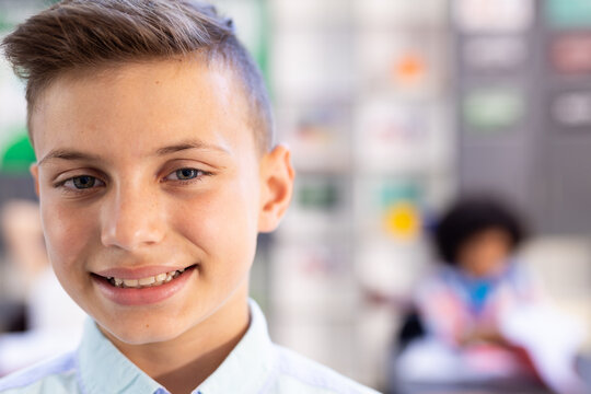 Portrait of happy smiling caucasian schoolboy in classroom, with copy space