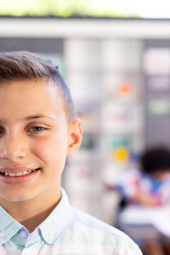 Half face portrait of happy, smiling caucasian schoolboy in classroom, with copy space