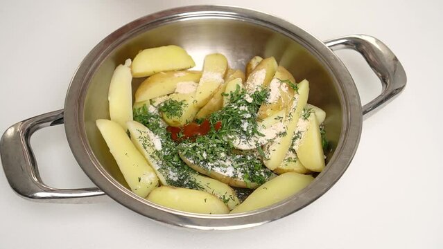 The cook puts the hot tabasco sauce in the pot with the sliced potatoes. Side view. Process and recipe for rustic or Idaho potatoes. Step by step. Step 11