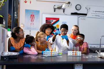 Diverse female teacher and school children doing an experiment in chemistry class - obrazy, fototapety, plakaty