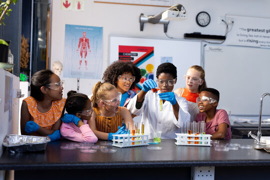 Diverse female teacher and school children doing an experiment in chemistry class