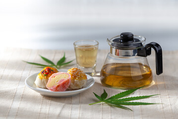Cake plate and marijuana leaf and teapot with teacup placed on a white background