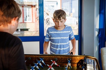 Two smiling school boys playing table soccer. Happy excited children having fun with family game...