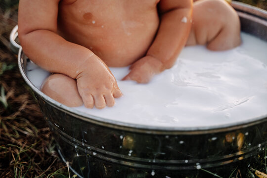 Child Swimming in Milk Bath Close-up Photography. Toddler Kid Swim and Bathing in Healthcare Milky Metallic Basin Bathtub Outdoor. Toddler Infant Recreational Hygiene Funny Time in Nature