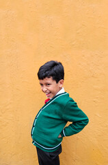 9-year-old dark-skinned Latino boy in school uniform suffers from back and neck pain from carrying a heavy backpack has muscle strain