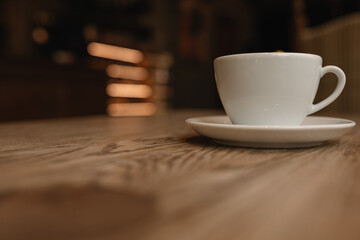 A white cup on wooden table with copy space. View from the bottom. An unrecognizable interior of...
