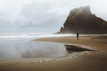 A shot of a model standing and looking into the distance on Piha beach in New Zealand