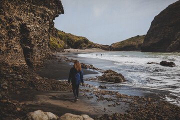 A shot of a model walking on a rocky beach in New Zealand