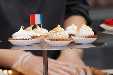 Sale of desserts and sweets at the French wine and food festival in holesovice, Prague. Closeup of metal tray with mini tarts with flambé meringue and French tricolor.