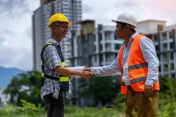 Civil engineer and construction worker manager holding a blueprint Discuss and agree planning on...