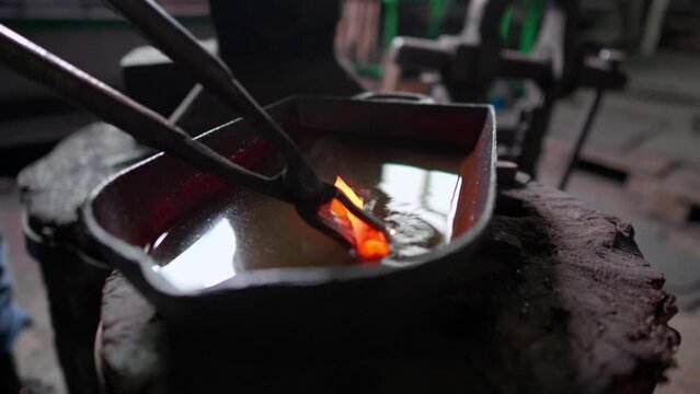 Blacksmith quenching hot metal arrowhead