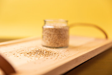 mixed raw quinoa in glass small jar on rustic wooden table on yellow background