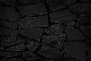 Old dark black stone brick wall texture with vintage style for background and design art work.