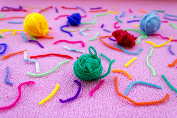 Close-up of colorful yarn balls and threads on pink ground