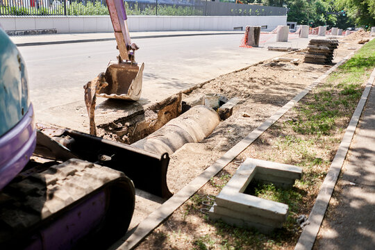 Big jackhammer drill drilling road.Heavy machinery crushing asphalt for stormwater drain repair. excavator tracks in the water. repair and expansion of a road