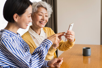 携帯電話の操作の仕方を娘に教わるシニア女性