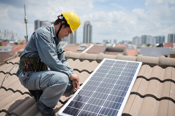 Worker in uniform and hardhat screwing solar panel on roof