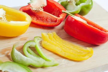 Set of colorful sliced fresh bell peppers on a wooden cutting board. Cook food with bell pepper as an ingredient.