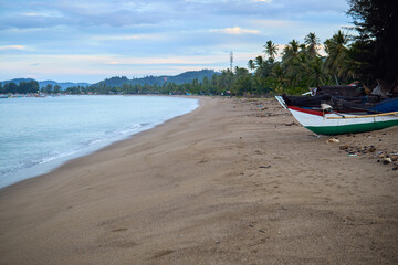 fishing boat on the beach with a blue sky and coconut tree in indonesia