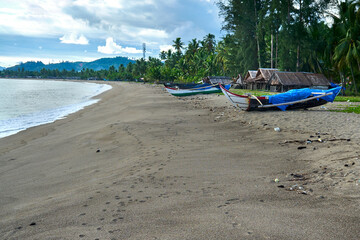 Fototapeta na wymiar fishing boat on the beach with a blue sky and coconut tree in indonesia