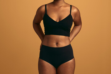 Crop black woman in underwear with hands behind back